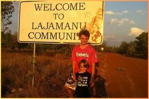 Two kids in front of the Welcome to Lajamanu sign